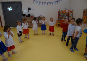 Dzieci stojąc w kole śpiewają piosenkę.