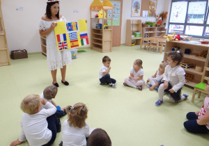 Dzieci patrzą na nauczycielkę z plakatem.