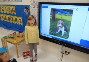 Dziewczynka pokazuje na tablecie zdjęcie swojego psa