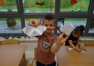 Chłopiec pokazuje zwierzątka z papieru