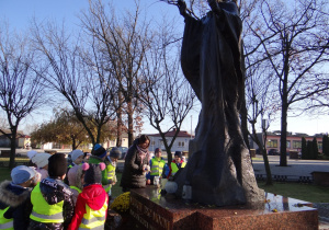 Dzieci stawiają znicz przy pomniku Jana Pawła II