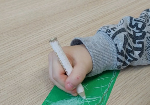 Chłopiec wypowiada ćwiczoną głoskę i rysuje góry i zimę